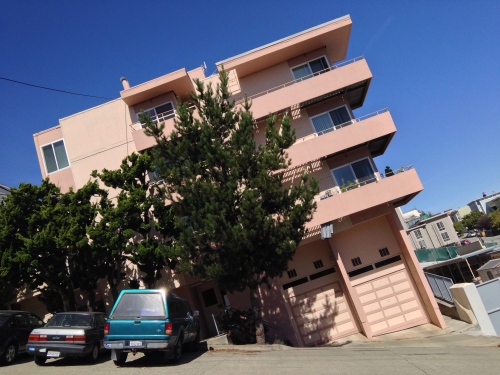 Apartment building and trees which are titled at a 30 degree angle to the street.